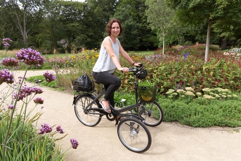 Eine Frau fährt auf einem Therapierad in einem Park